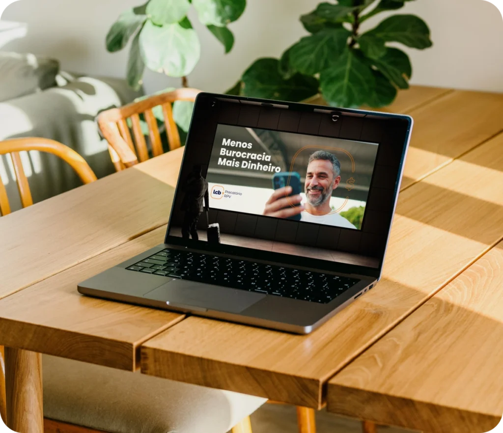Laptop aberto com tela exibindo homem sorrindo e texto "Menos Burocracia Mais Dinheiro